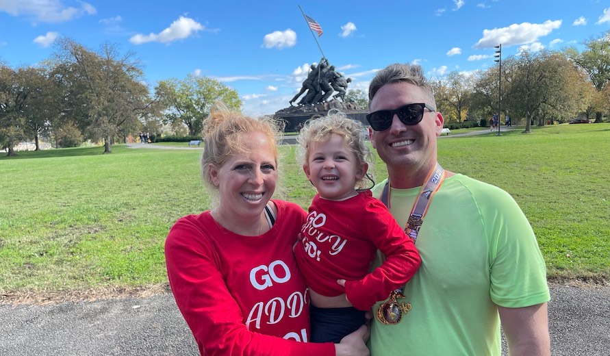woman, child and man with marathon finishers medal in front of Iwo Jima statue
