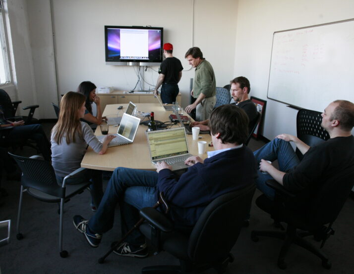 people sitting around a conference table with a screen