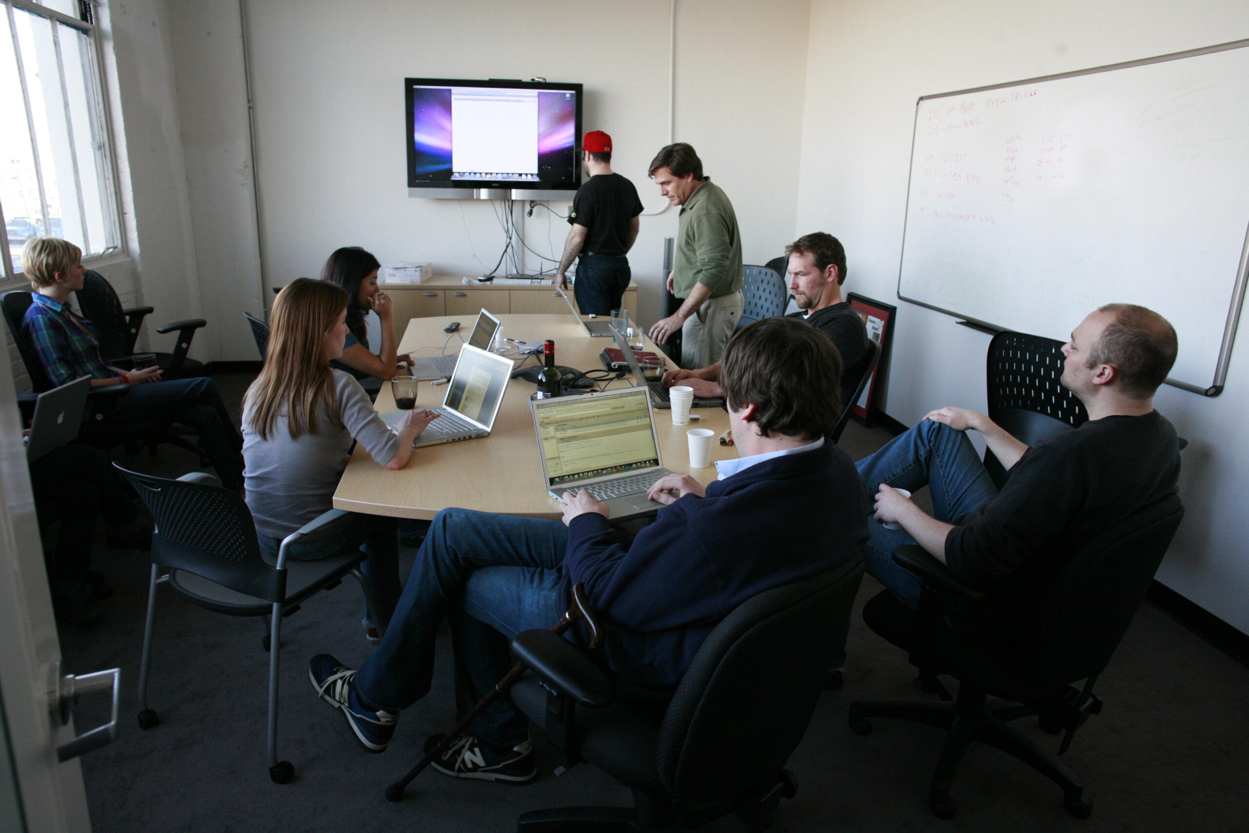 people sitting around a conference table with a screen