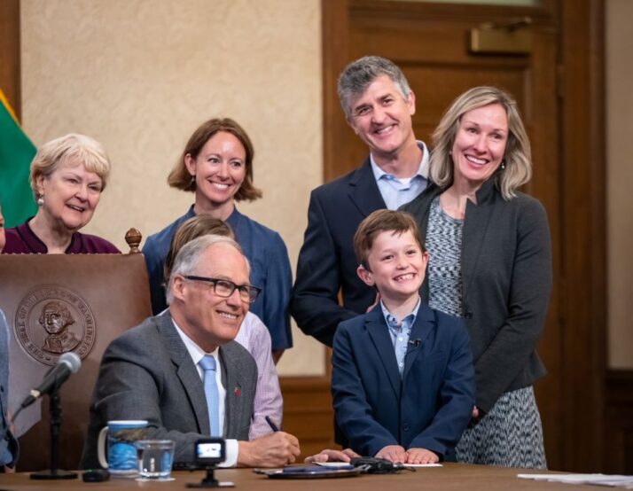 Boy smiles with governor on signing a bill into law